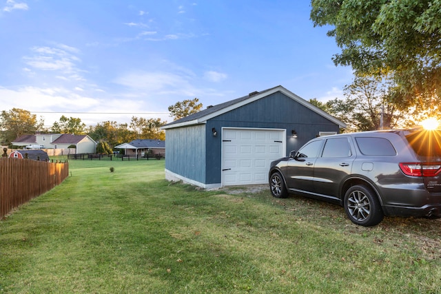 view of side of property featuring a garage, a lawn, and an outbuilding