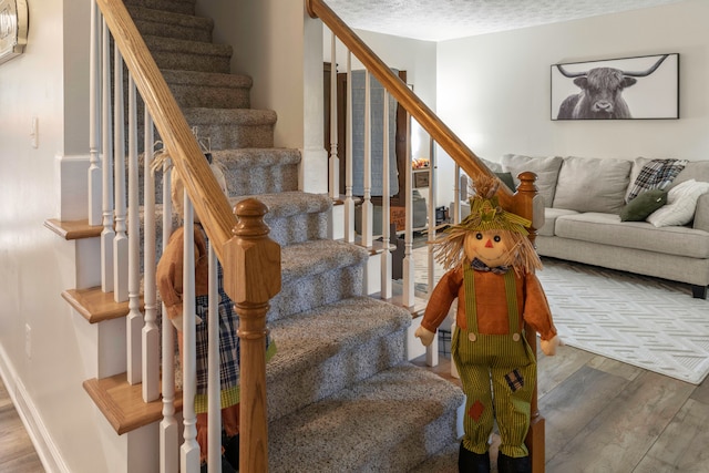 stairs featuring a textured ceiling and wood-type flooring