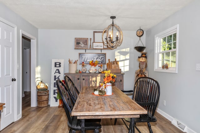 dining space featuring wood-type flooring and a notable chandelier