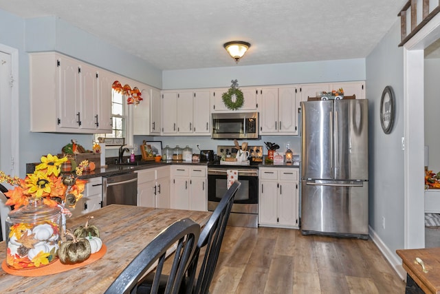 kitchen featuring a textured ceiling, hardwood / wood-style flooring, sink, white cabinets, and appliances with stainless steel finishes