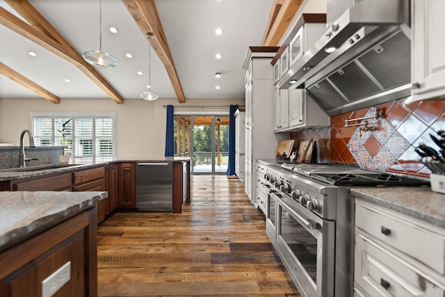 kitchen with exhaust hood, range with two ovens, white cabinets, and a wealth of natural light