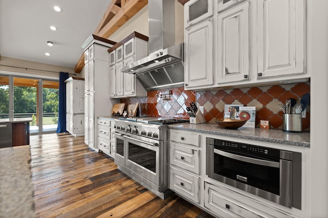 kitchen with dark wood-type flooring, white cabinetry, wall chimney exhaust hood, stainless steel appliances, and decorative backsplash