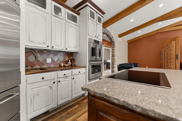 kitchen featuring sink, backsplash, white cabinetry, stainless steel appliances, and dark hardwood / wood-style flooring