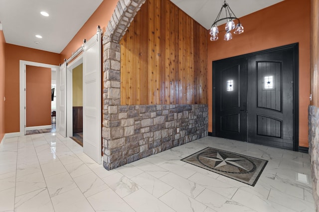 foyer featuring a notable chandelier, wooden walls, and a barn door