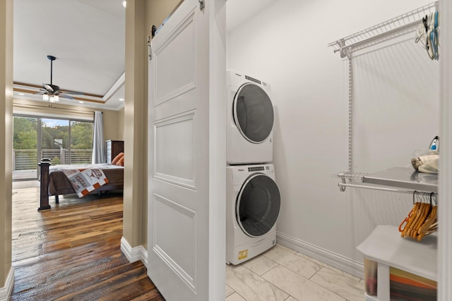 laundry room with a barn door, light wood-type flooring, ceiling fan, and stacked washer / dryer