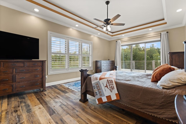 bedroom with a tray ceiling, ornamental molding, dark wood-type flooring, and ceiling fan