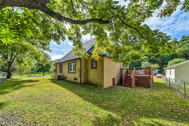 view of side of property with cooling unit, a deck, and a lawn