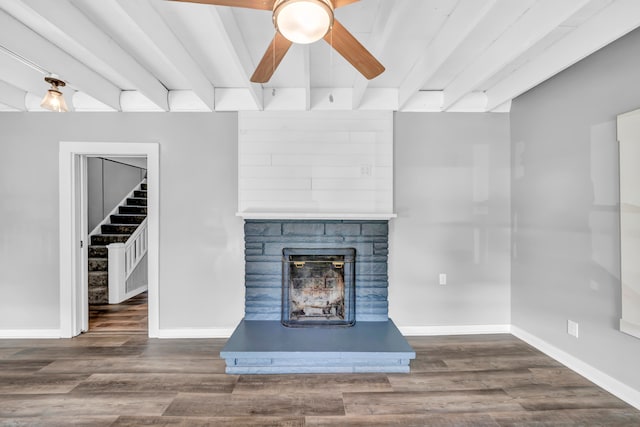 unfurnished living room featuring a stone fireplace, ceiling fan, beamed ceiling, and dark wood-type flooring