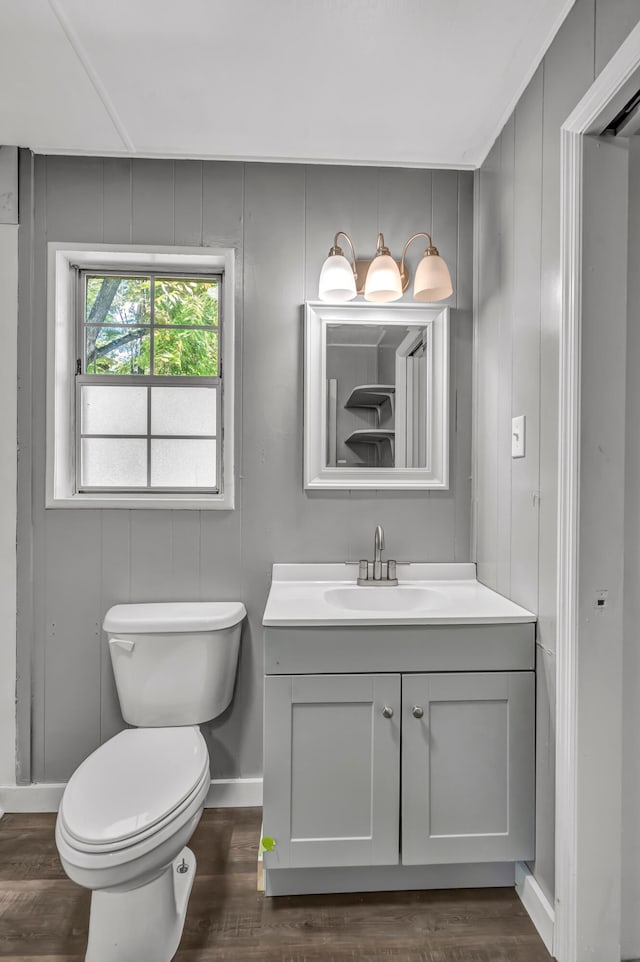 bathroom featuring hardwood / wood-style floors, vanity, toilet, and wood walls