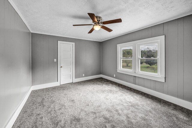 empty room with ornamental molding, ceiling fan, carpet floors, and a textured ceiling