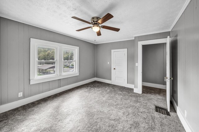 unfurnished bedroom with carpet floors, a textured ceiling, ornamental molding, and ceiling fan