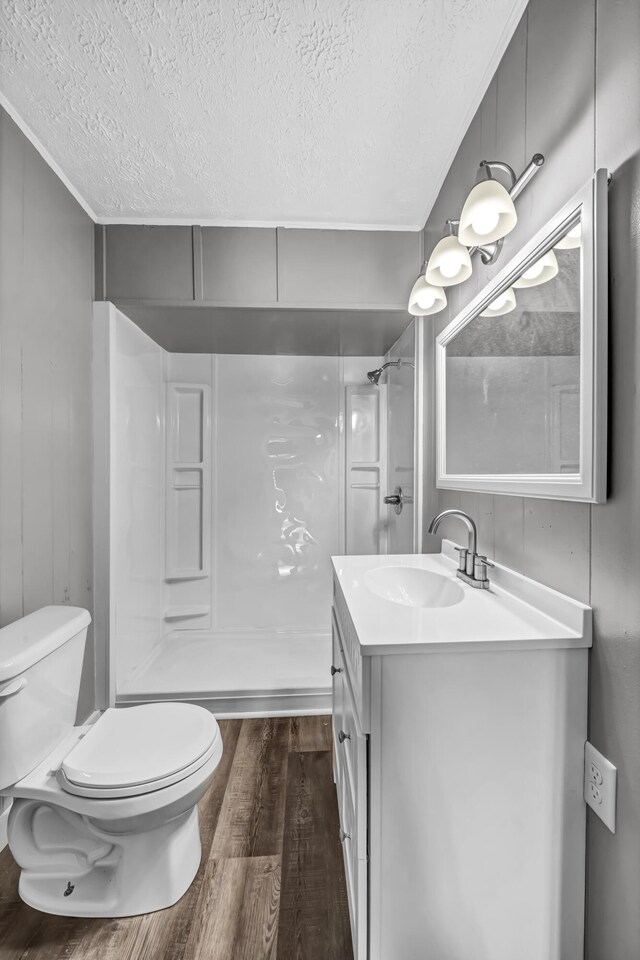 bathroom featuring vanity, a textured ceiling, walk in shower, hardwood / wood-style flooring, and toilet