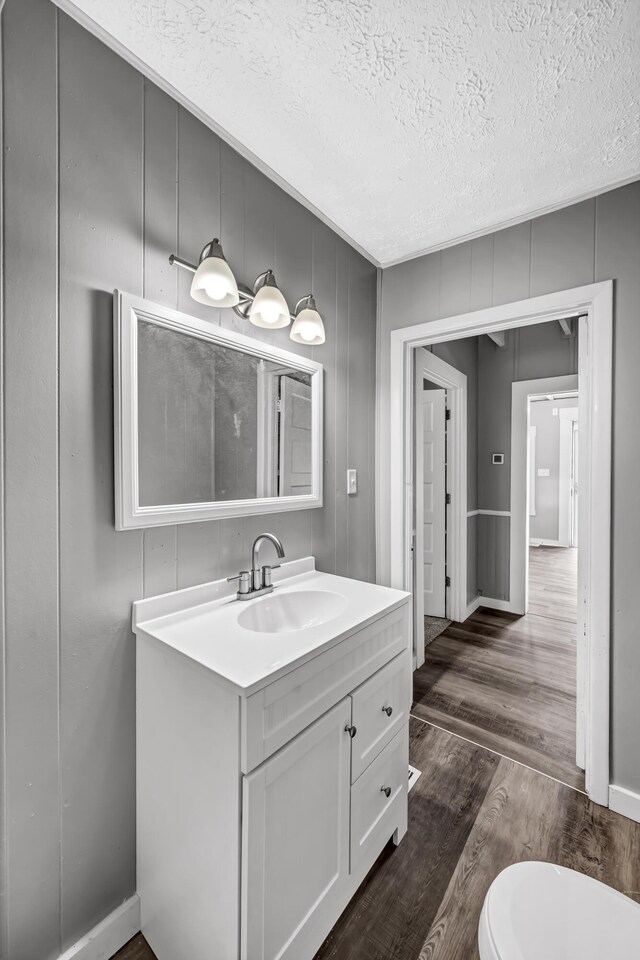 bathroom with a textured ceiling, vanity, toilet, and hardwood / wood-style flooring