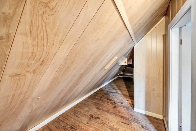 bonus room with vaulted ceiling, wood walls, and dark wood-type flooring