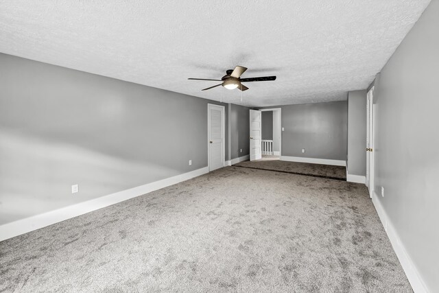 carpeted spare room featuring ceiling fan and a textured ceiling