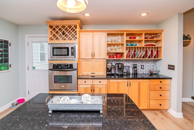 kitchen with stainless steel appliances, light brown cabinets, light hardwood / wood-style floors, and dark stone counters