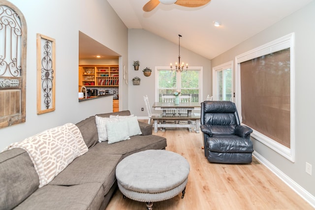 living room featuring lofted ceiling, ceiling fan with notable chandelier, and light wood-type flooring