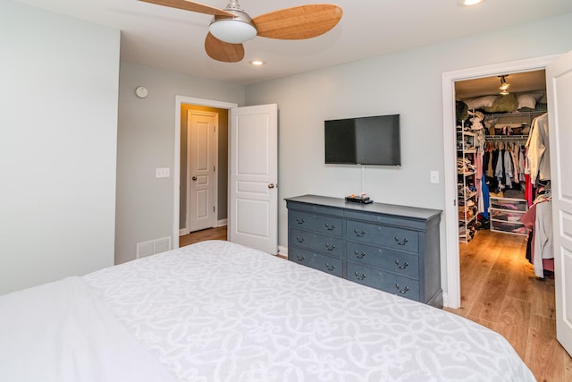 bedroom featuring ceiling fan, a spacious closet, light hardwood / wood-style floors, and a closet