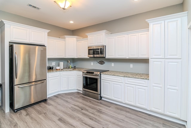 kitchen featuring stainless steel appliances, white cabinetry, sink, and light wood-type flooring