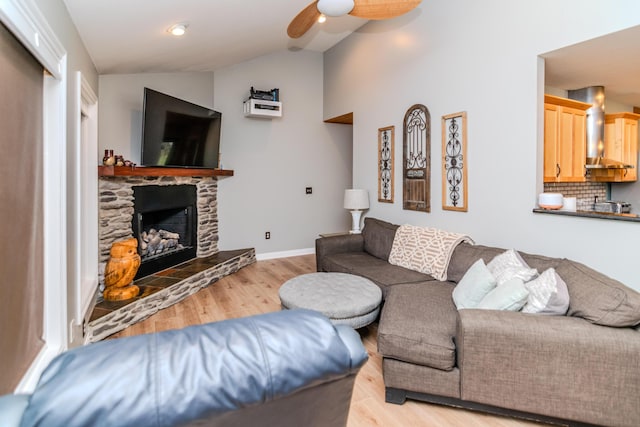 living room featuring a fireplace, vaulted ceiling, light hardwood / wood-style floors, and ceiling fan