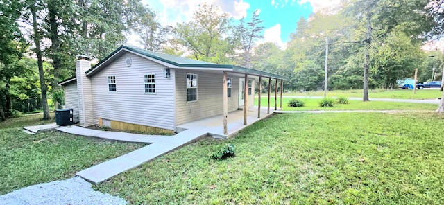 view of side of home with a lawn, a patio area, and central AC