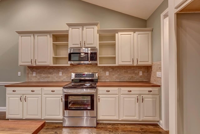 kitchen with appliances with stainless steel finishes, dark wood-type flooring, vaulted ceiling, and wood counters