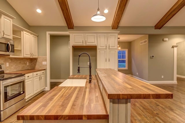 kitchen with a center island, white cabinetry, butcher block counters, hanging light fixtures, and stainless steel appliances