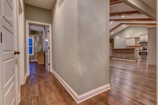 hallway with sink, lofted ceiling with beams, and dark hardwood / wood-style flooring