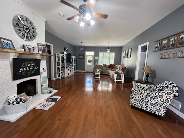 living room featuring ceiling fan, a fireplace, and dark wood-type flooring