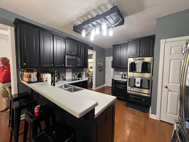 kitchen with appliances with stainless steel finishes, a kitchen breakfast bar, kitchen peninsula, and dark hardwood / wood-style flooring