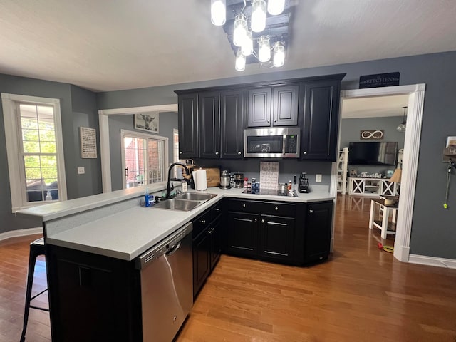 kitchen with light hardwood / wood-style floors, appliances with stainless steel finishes, sink, and kitchen peninsula