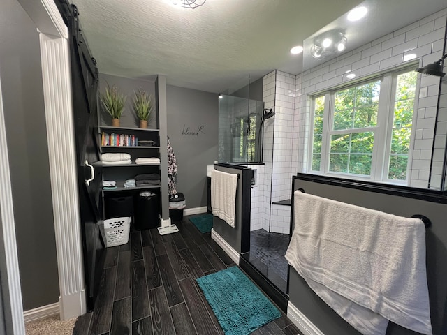 bathroom featuring a textured ceiling, hardwood / wood-style flooring, and a shower with shower door