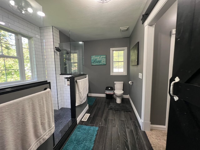 bathroom featuring wood-type flooring, a textured ceiling, walk in shower, and toilet