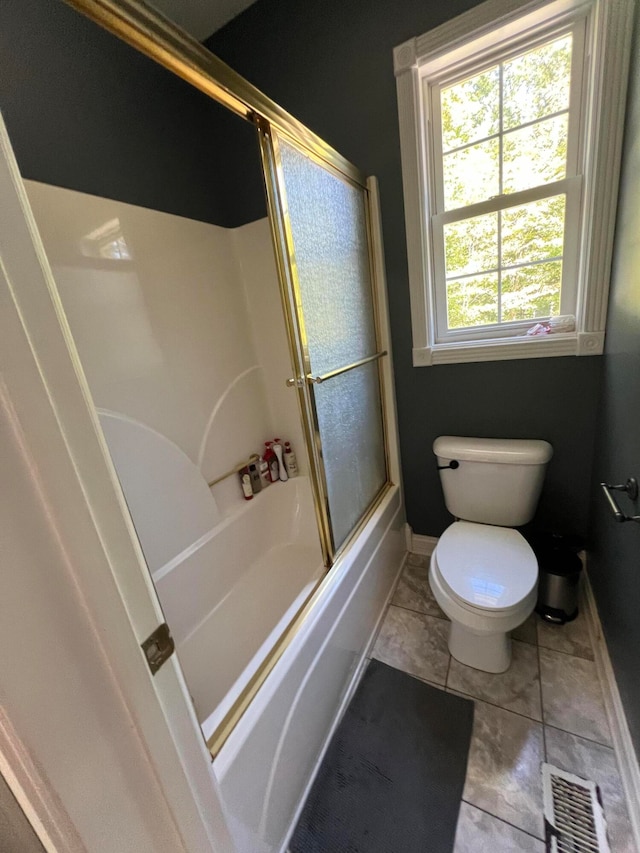 bathroom featuring enclosed tub / shower combo, toilet, and tile patterned floors