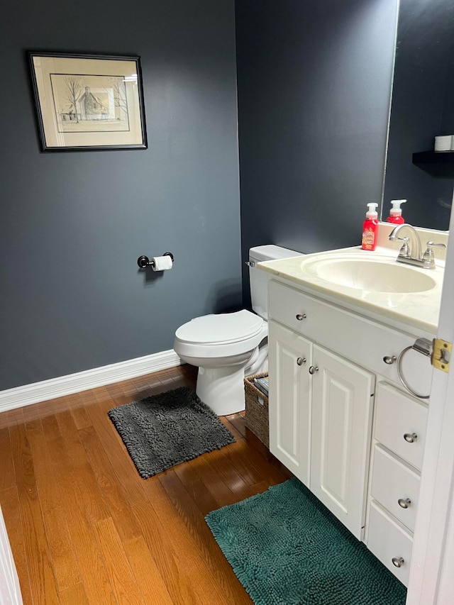 bathroom with wood-type flooring, vanity, and toilet