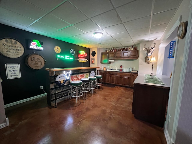 interior space with a drop ceiling and dark brown cabinets