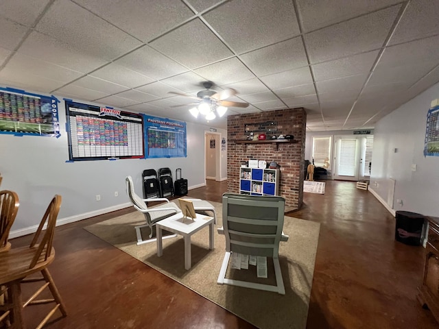 living room with ceiling fan, a paneled ceiling, and concrete flooring