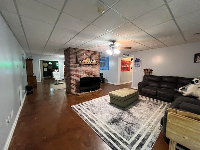 living room featuring a paneled ceiling, ceiling fan, and a brick fireplace