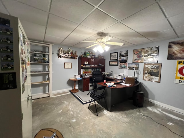 office with a drop ceiling, concrete flooring, and ceiling fan