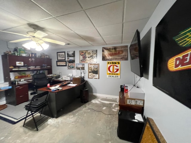 office area with ceiling fan, a drop ceiling, and concrete floors