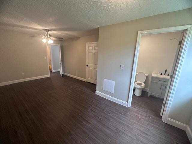 interior space with connected bathroom, a textured ceiling, ceiling fan, dark hardwood / wood-style floors, and sink