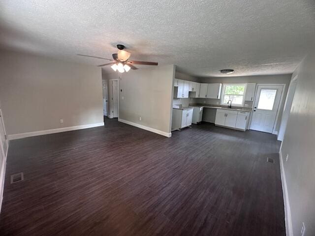 unfurnished living room with a textured ceiling, dark hardwood / wood-style flooring, ceiling fan, and sink