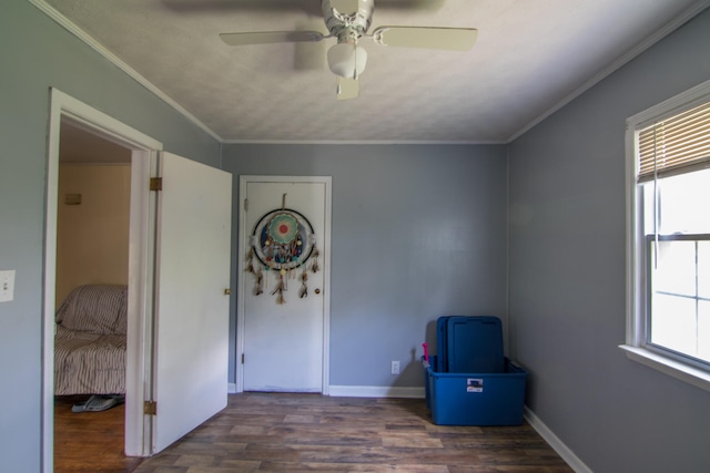 unfurnished bedroom featuring ceiling fan, multiple windows, dark wood-type flooring, and crown molding