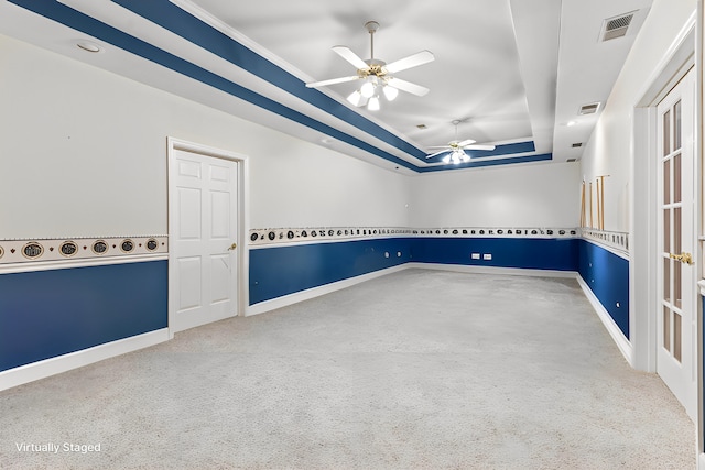 carpeted spare room with ceiling fan and a raised ceiling