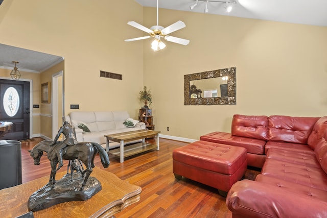 living room with ceiling fan, ornamental molding, high vaulted ceiling, rail lighting, and hardwood / wood-style floors