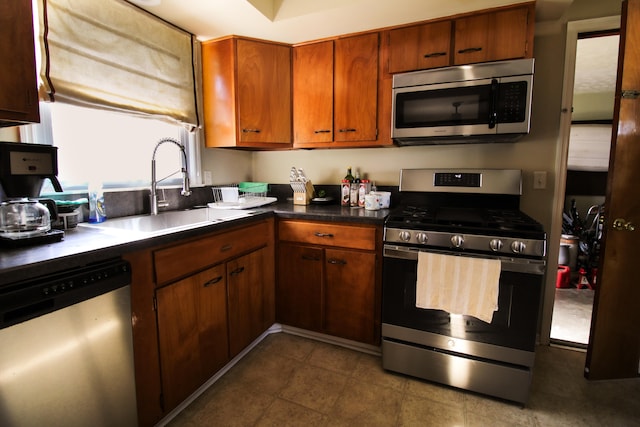 kitchen with dark tile patterned floors, stainless steel appliances, and sink