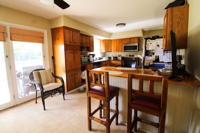 kitchen featuring kitchen peninsula, stove, and ceiling fan