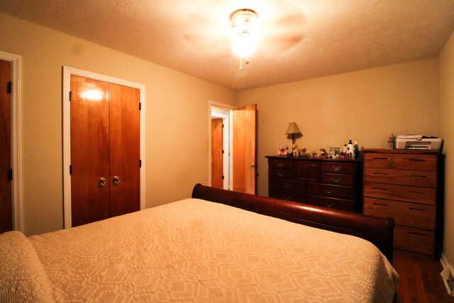 bedroom with a closet, ceiling fan, dark wood-type flooring, and a textured ceiling