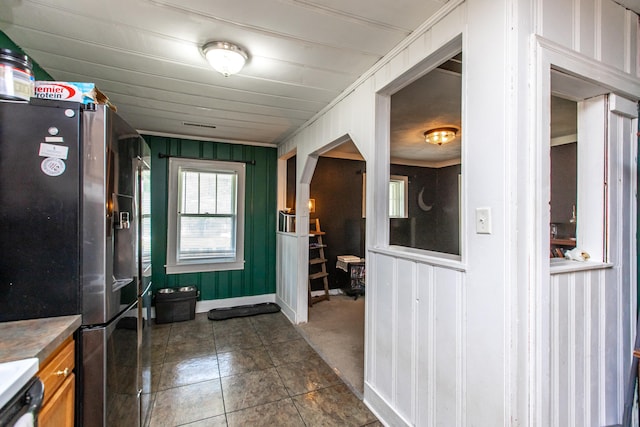 interior space featuring wood walls, ornamental molding, and dark tile patterned floors