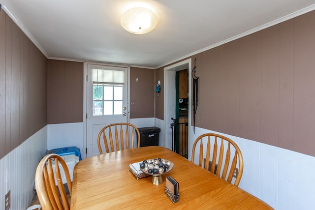 dining area with wooden walls and crown molding